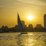 A felluca saling on the Nile at sunset, in the background Cairo's skyline.